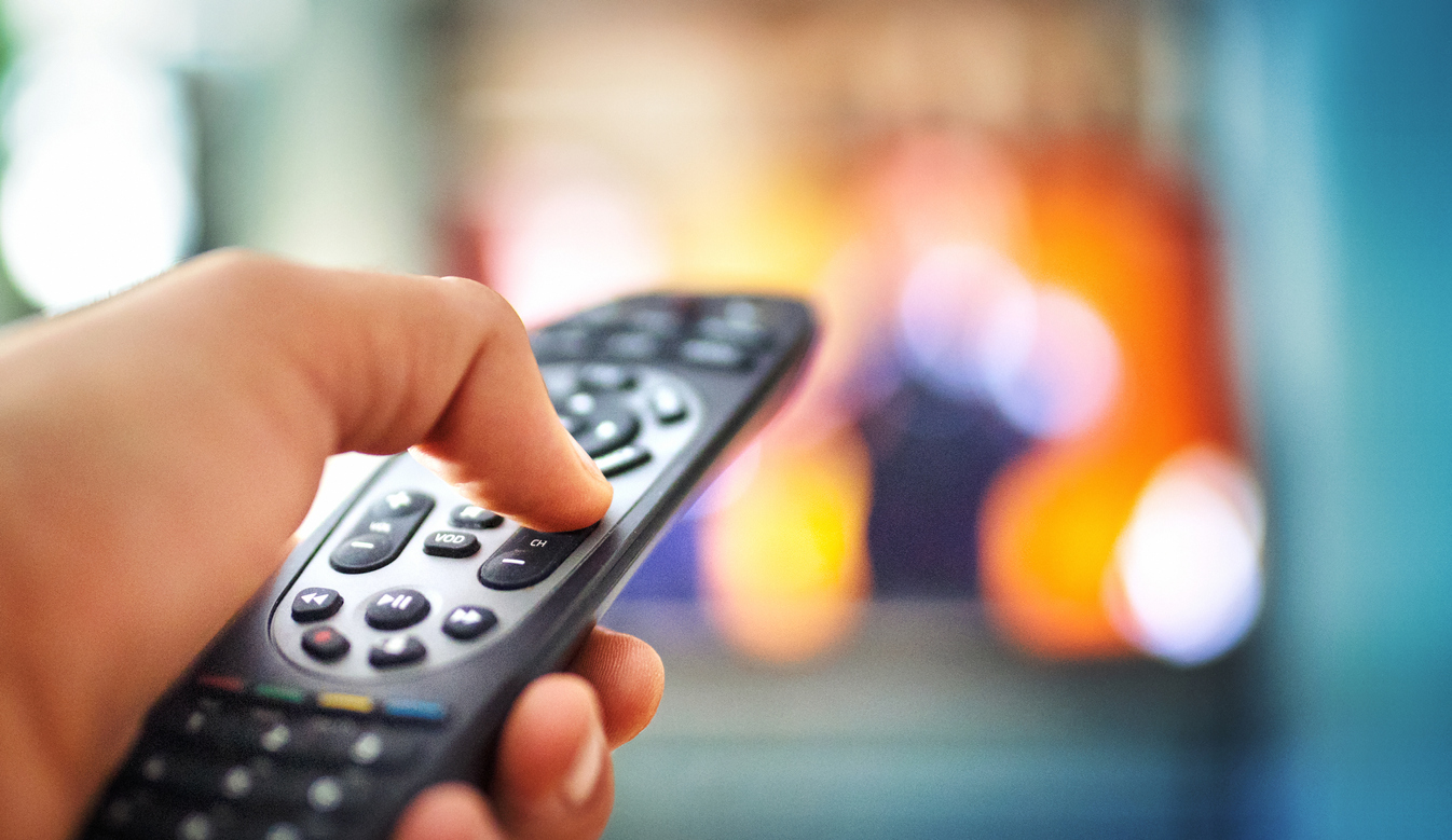 man watching tv and changing channels with a remote