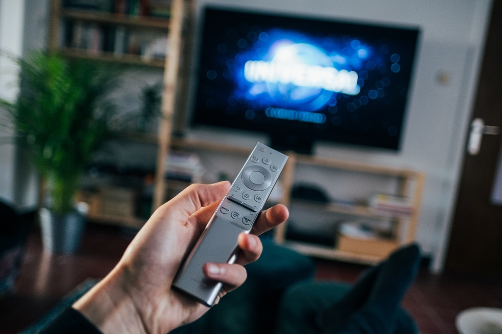  man holds Samsung OneRemote in front of his TV in living room
