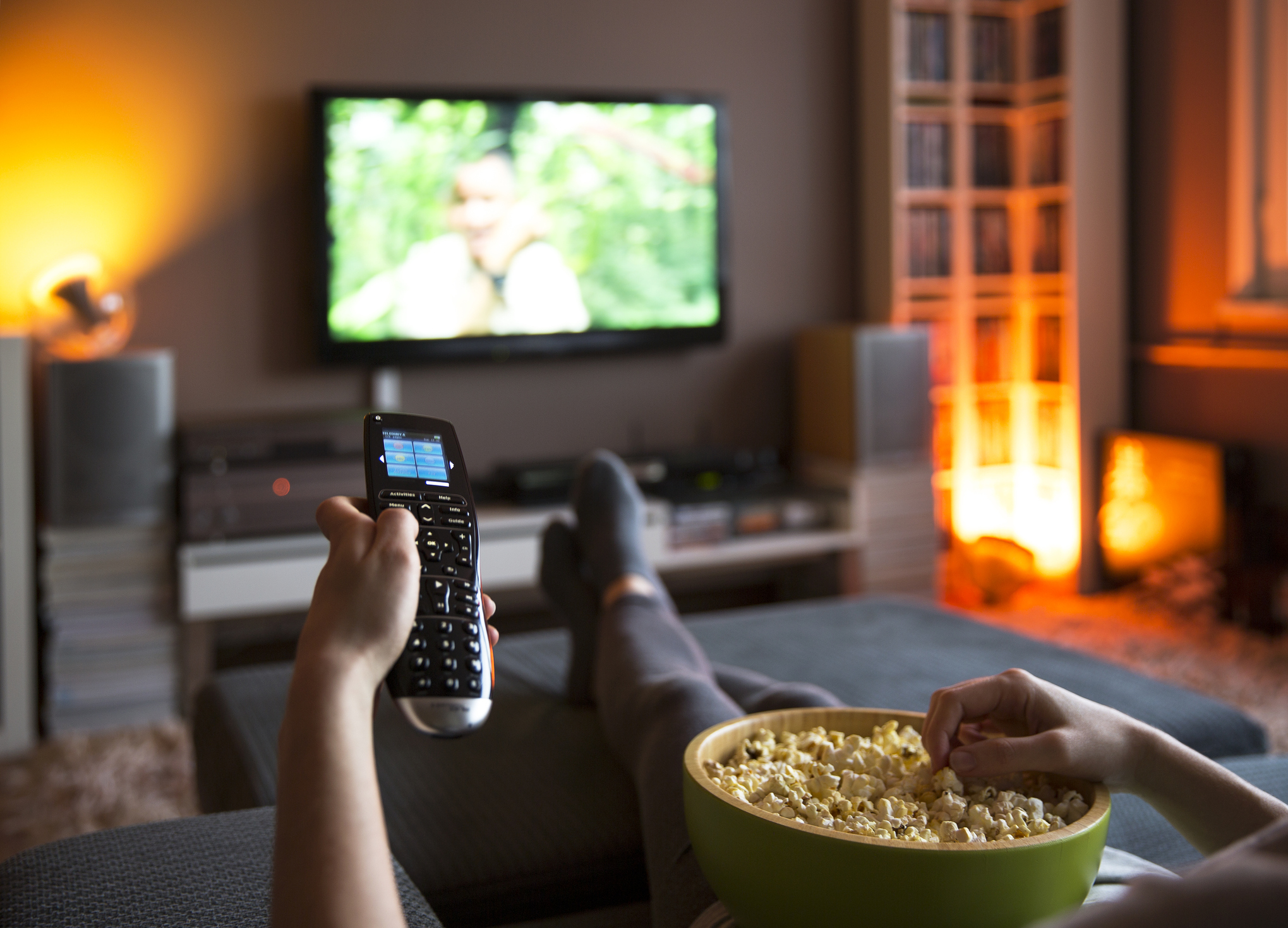 person holding the remote and eating popcorn while watching TV