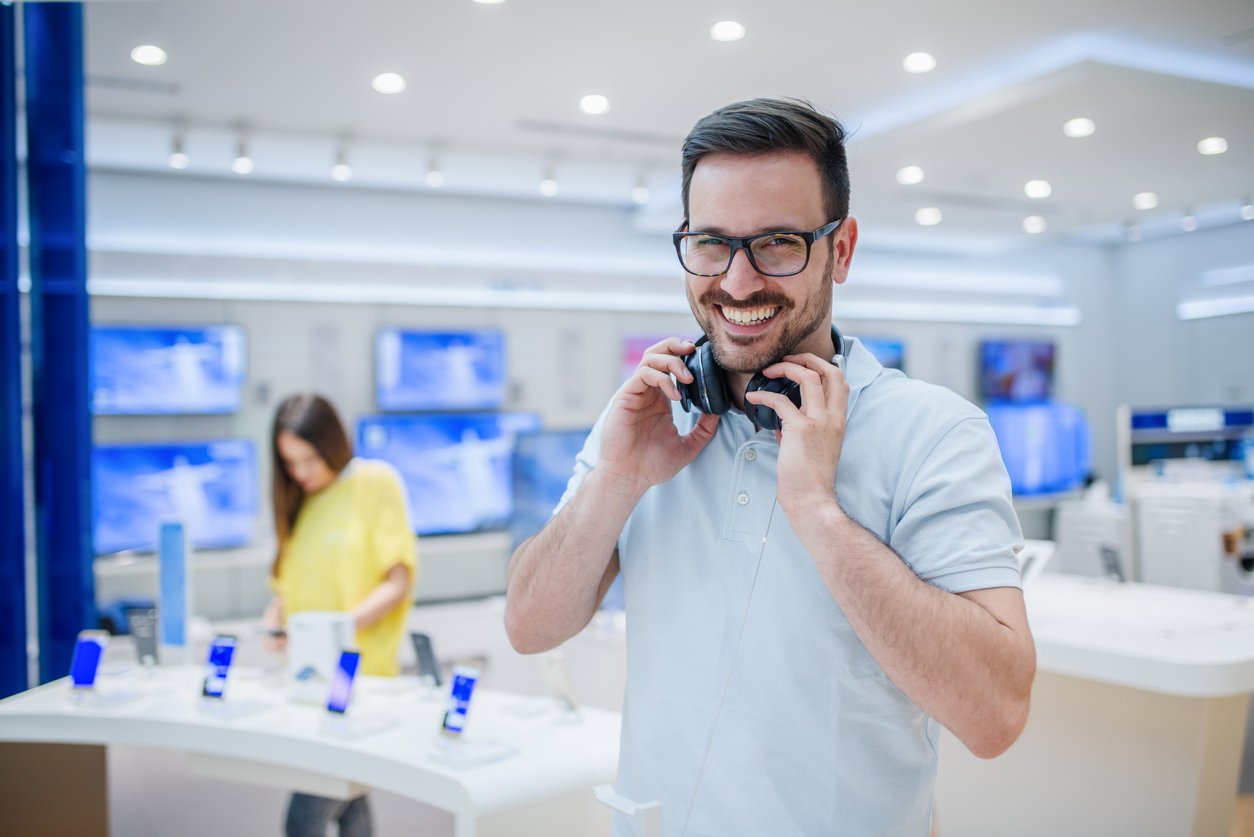 happy man posing with headphones in tech store
