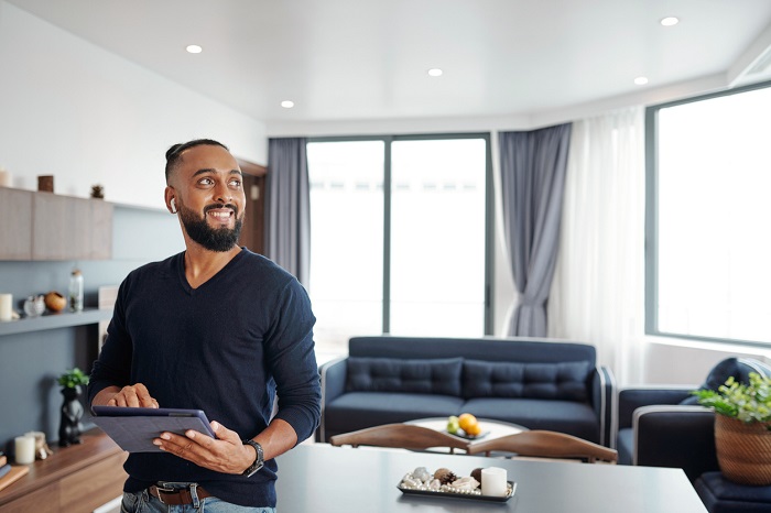 Bearded man using smart home application on digital tablet.