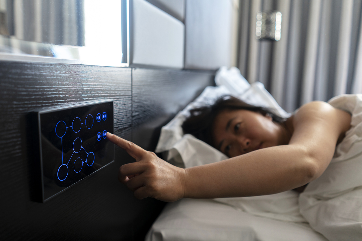Woman wakes up in smart bedroom and hits touchscreen to open shades