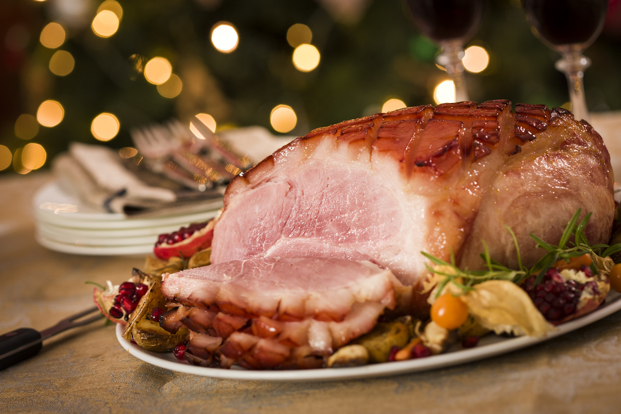 traditional glazed holiday ham with Christmas decorations in the background