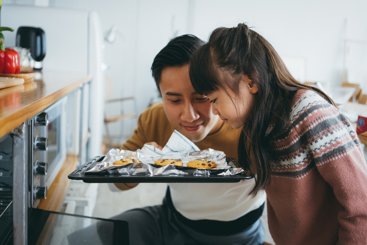 father and daughter smelling freshly baked chocolate chip cookies