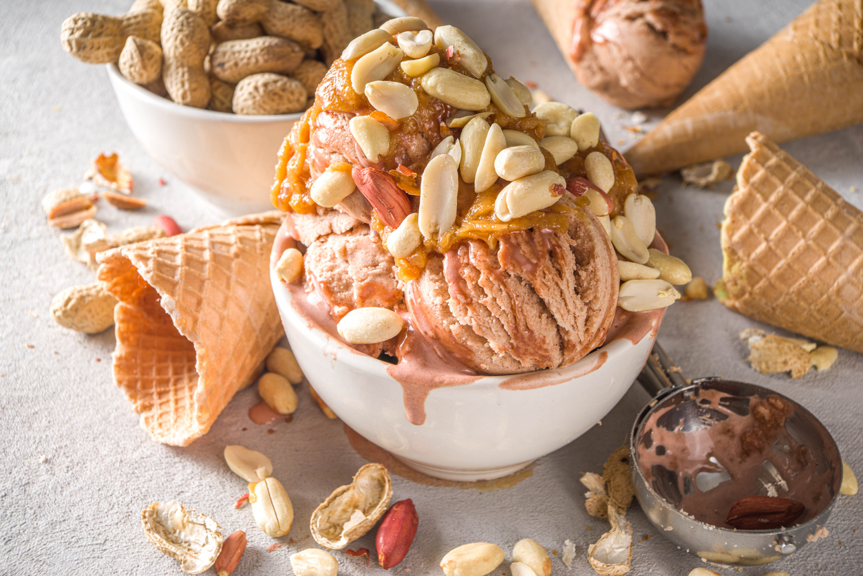sweet peanut ice cream with peanut butter topping and a lot of unshelled peanuts