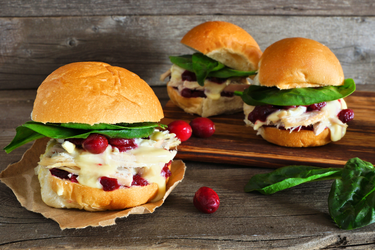 roasted turkey sandwiches with cranberry sauce and cheese against wood