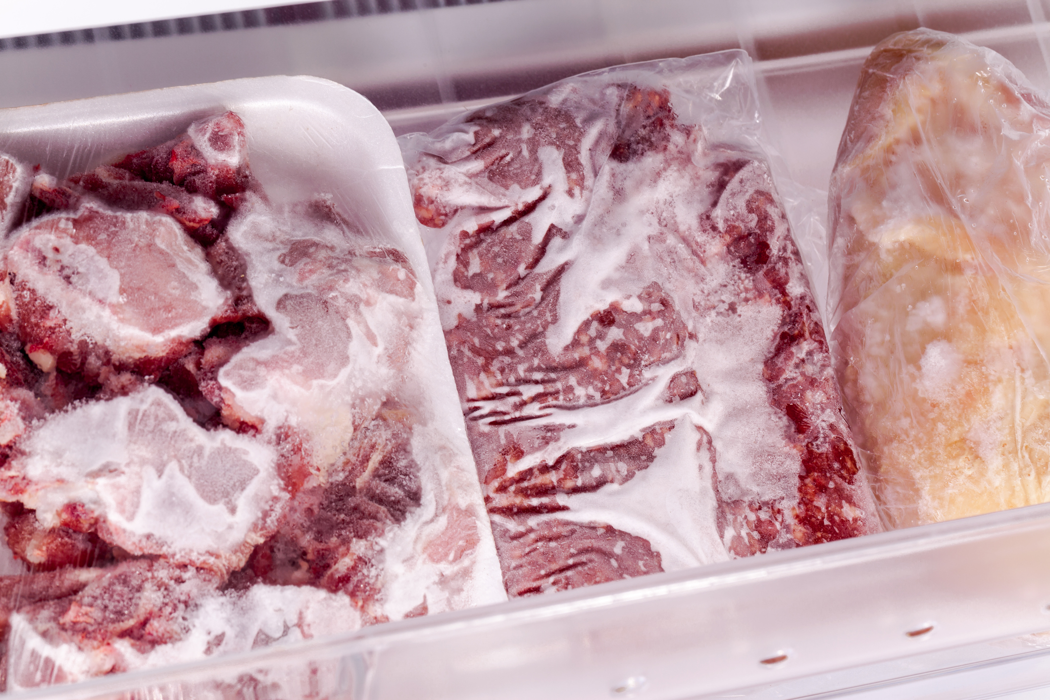 Frozen packages of various meats with freezer burn