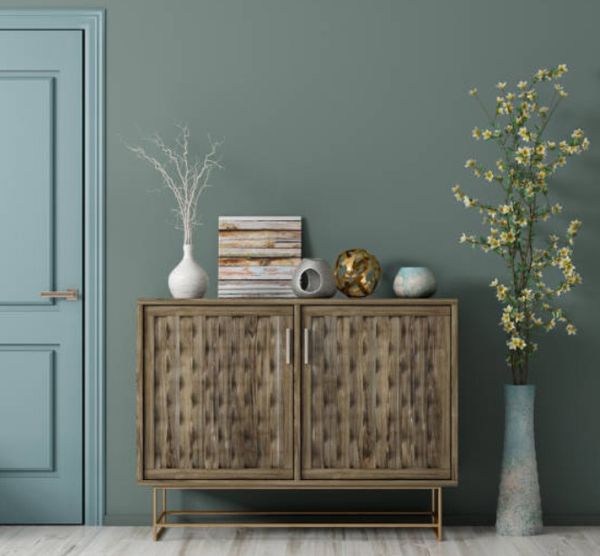 front view of a medium teal wall and door with a brown entryway cabinet styled with miscellaneous items