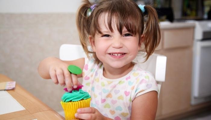 Little girl decorating a cupcake
