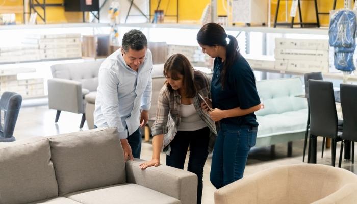 couple picking out a sofa with saleswoman