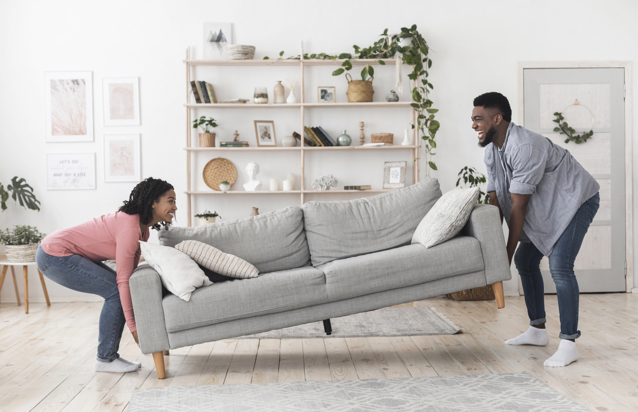 smiling couple move sofa in place