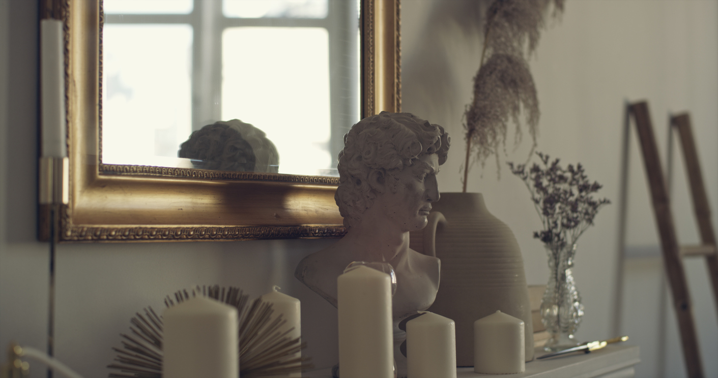 dimly lit corner of room with gilded mirror and Grecian bust