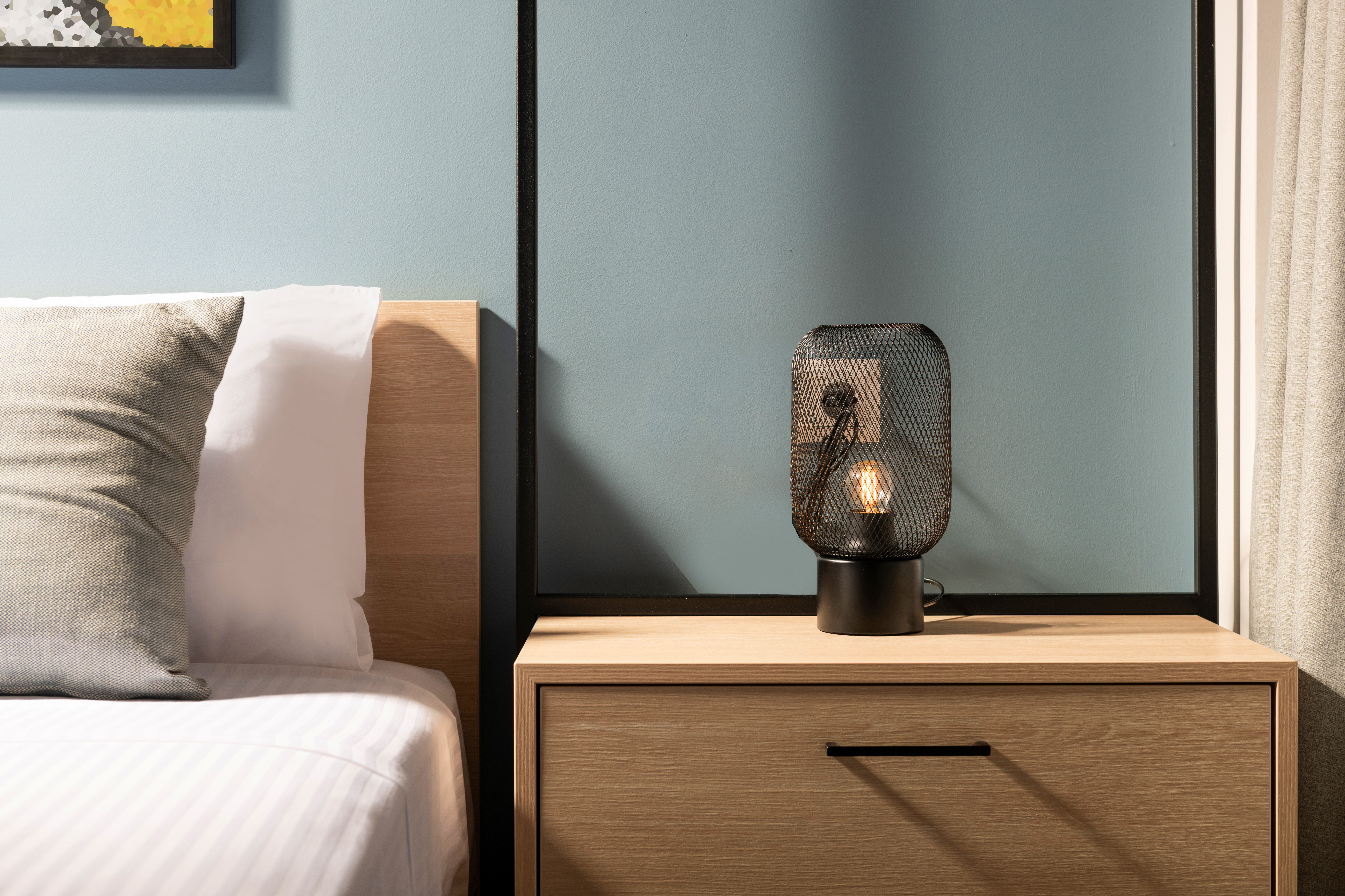 An industrial lamp shown on a wooden nightstand 