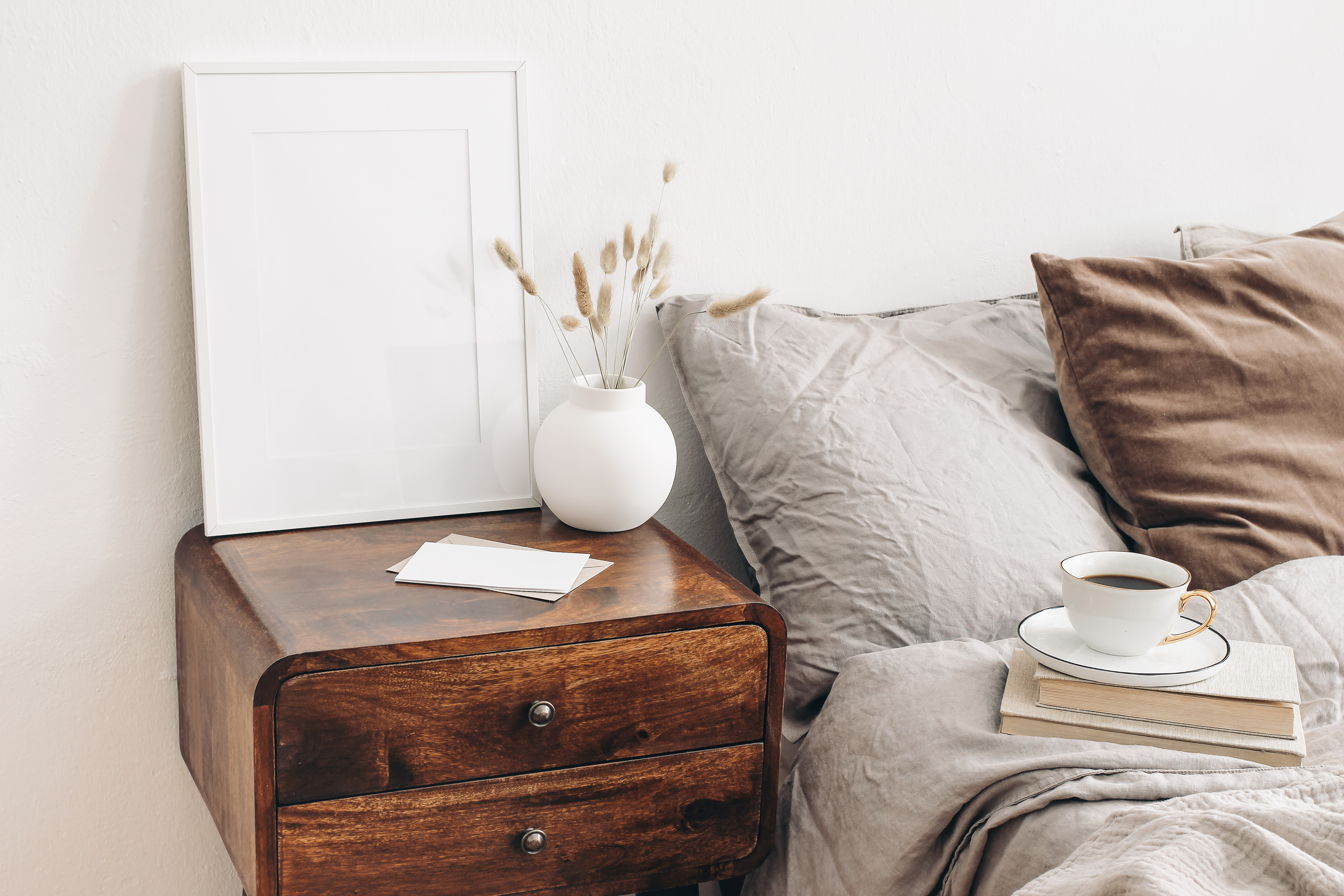 A mid-century modern nightstand featured with décor, books, and a cup of coffee 
