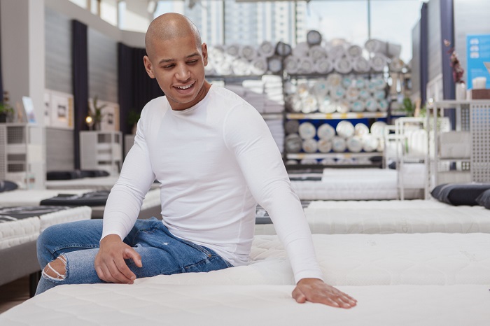 Man trying out mattress at furniture store.