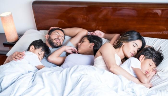Family sleeping together in one bed