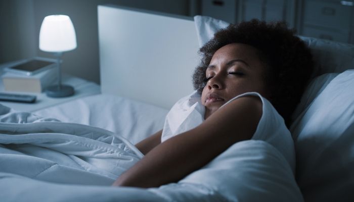 woman sleeping snuggled with pillow next to lamp