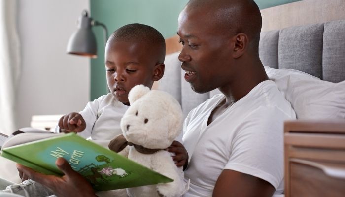 father and son reading book before bed