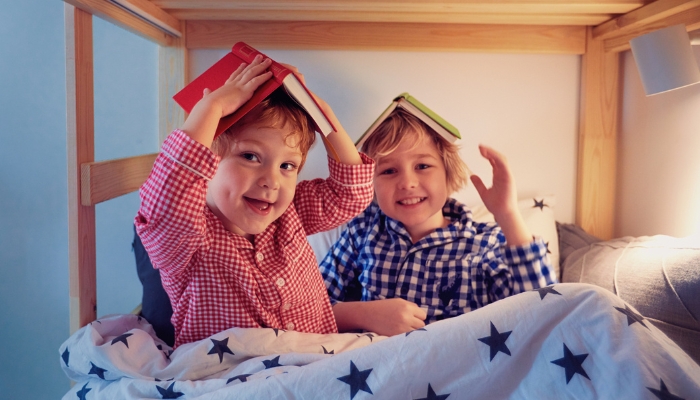 Two kids sharing the bottom bunk with books in their hands