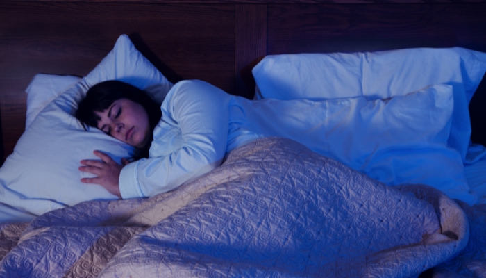 Woman sleeping comfortably in temperature-regulated room with blankets