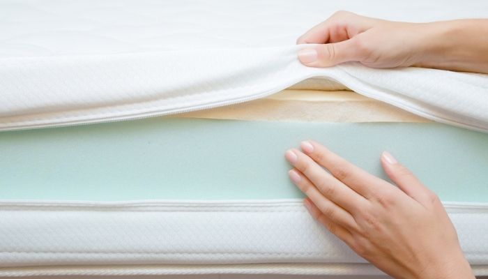 hand touching different layers of foam mattress