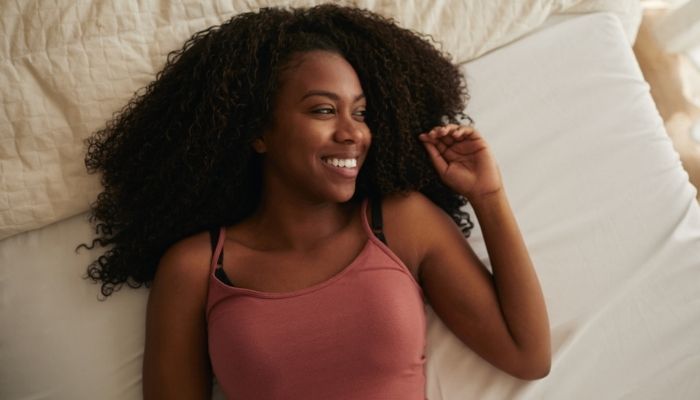 woman smiling while lying on her bed