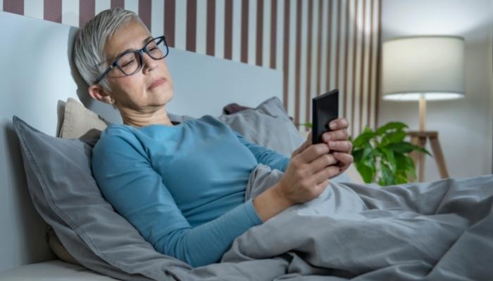 Woman looking at phone while in bed