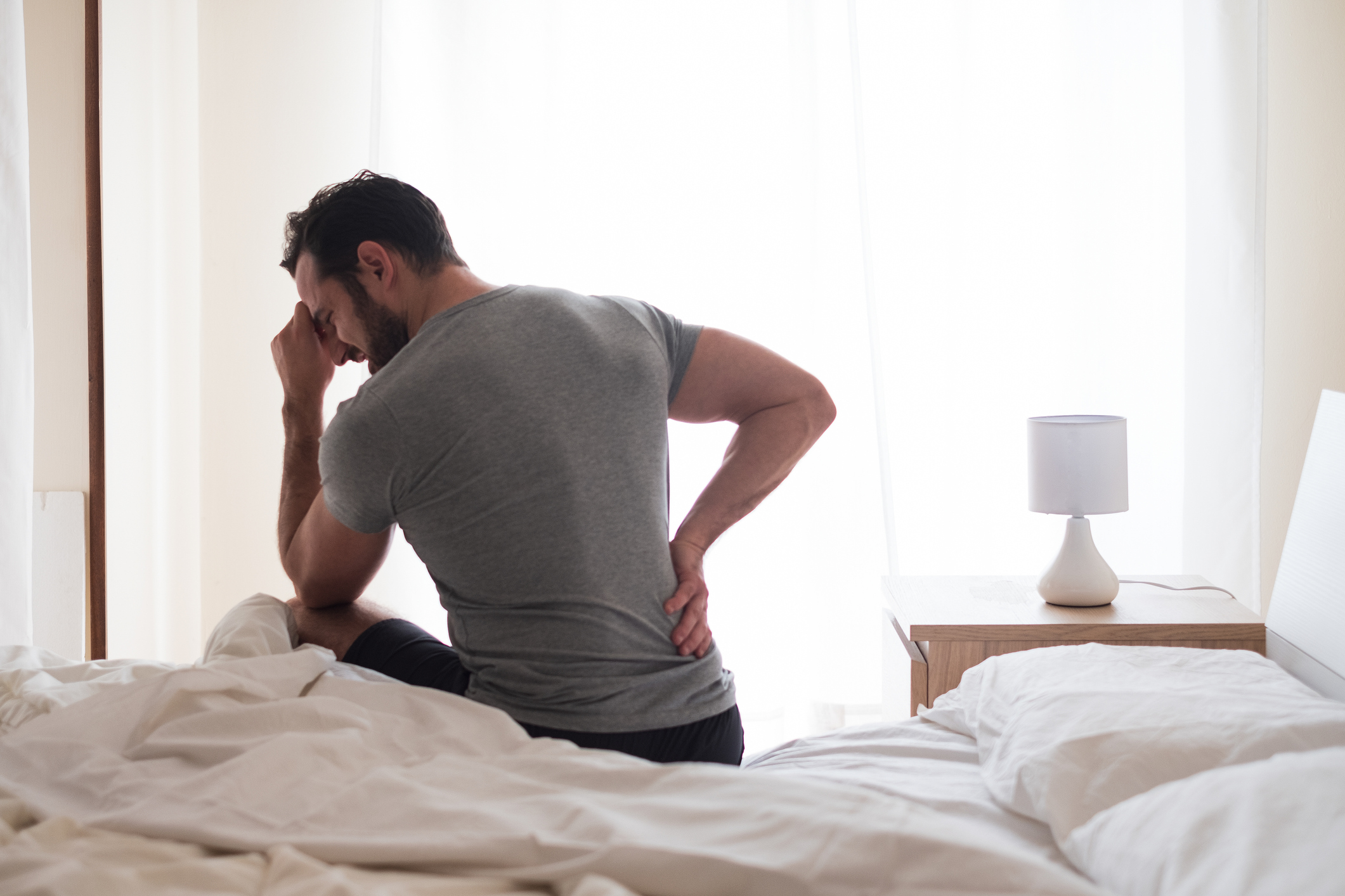 man waking with back pain in bed