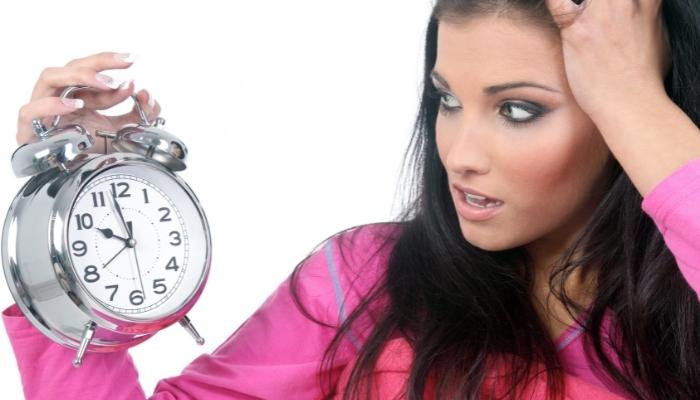 Woman staring at alarm clock in disbelief