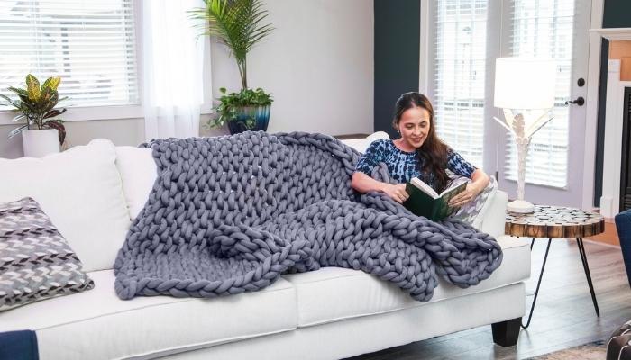 Woman reading a book with knitted heavy blanket around her