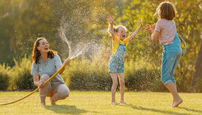 mother and daughters playing with sprinklers.