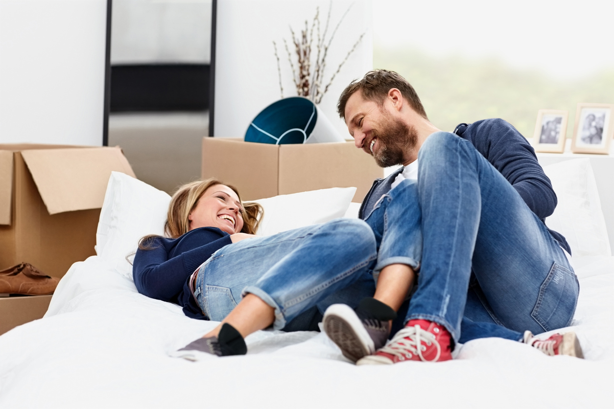 smiling couple relaxing by boxes in their new house
