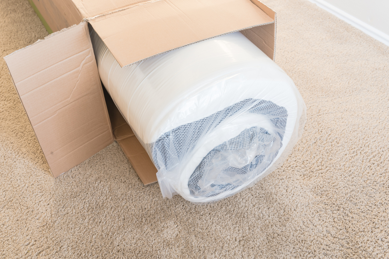 new roll-packed spring mattresses on carpet floor of apartment bedroom