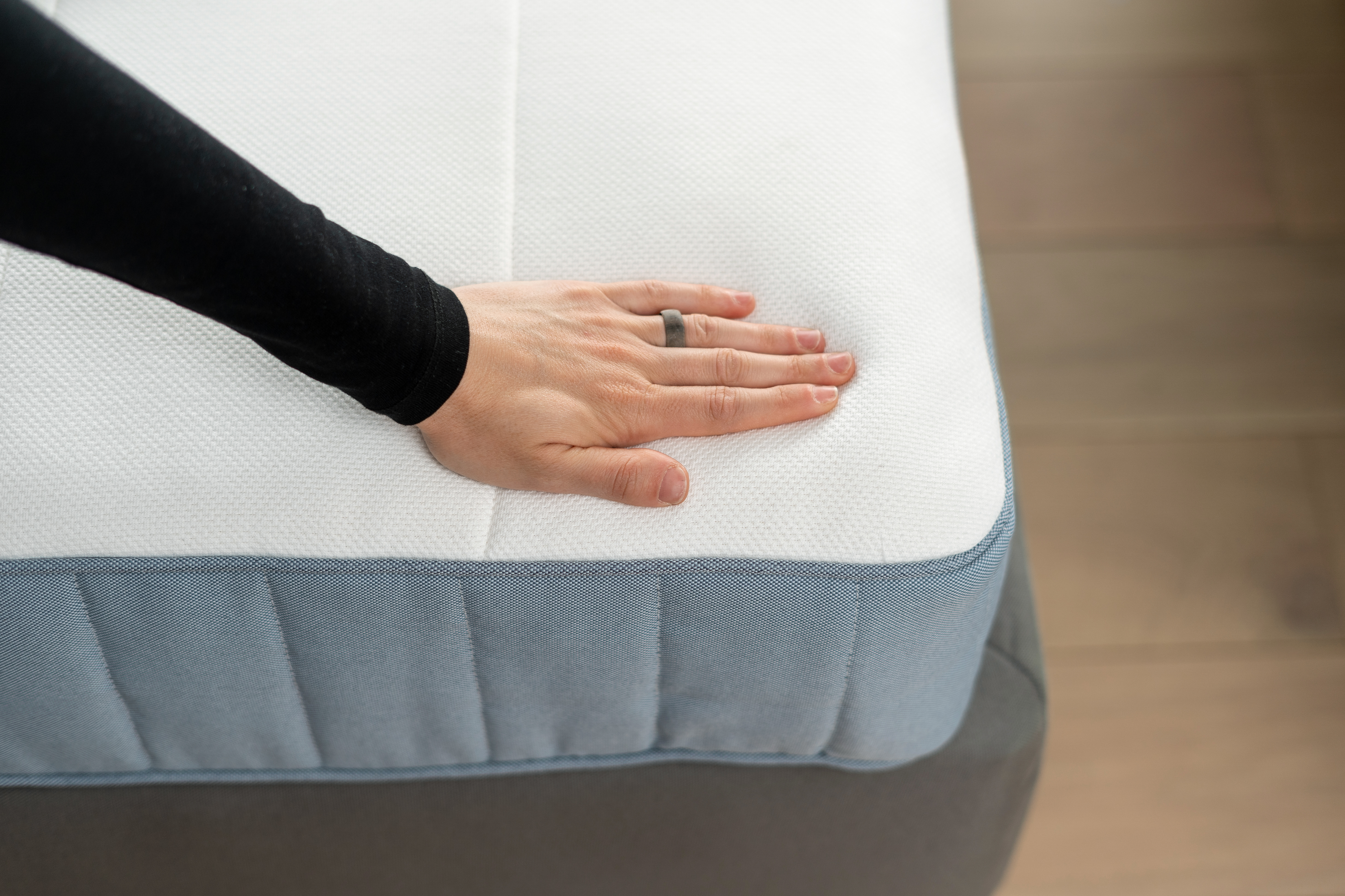 A person pressing down on a mattress 