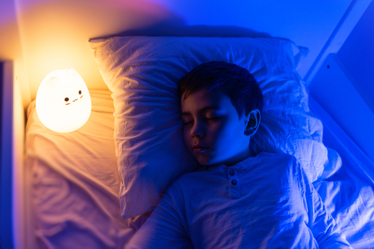 young boy sleeps on top bunk with nightlight