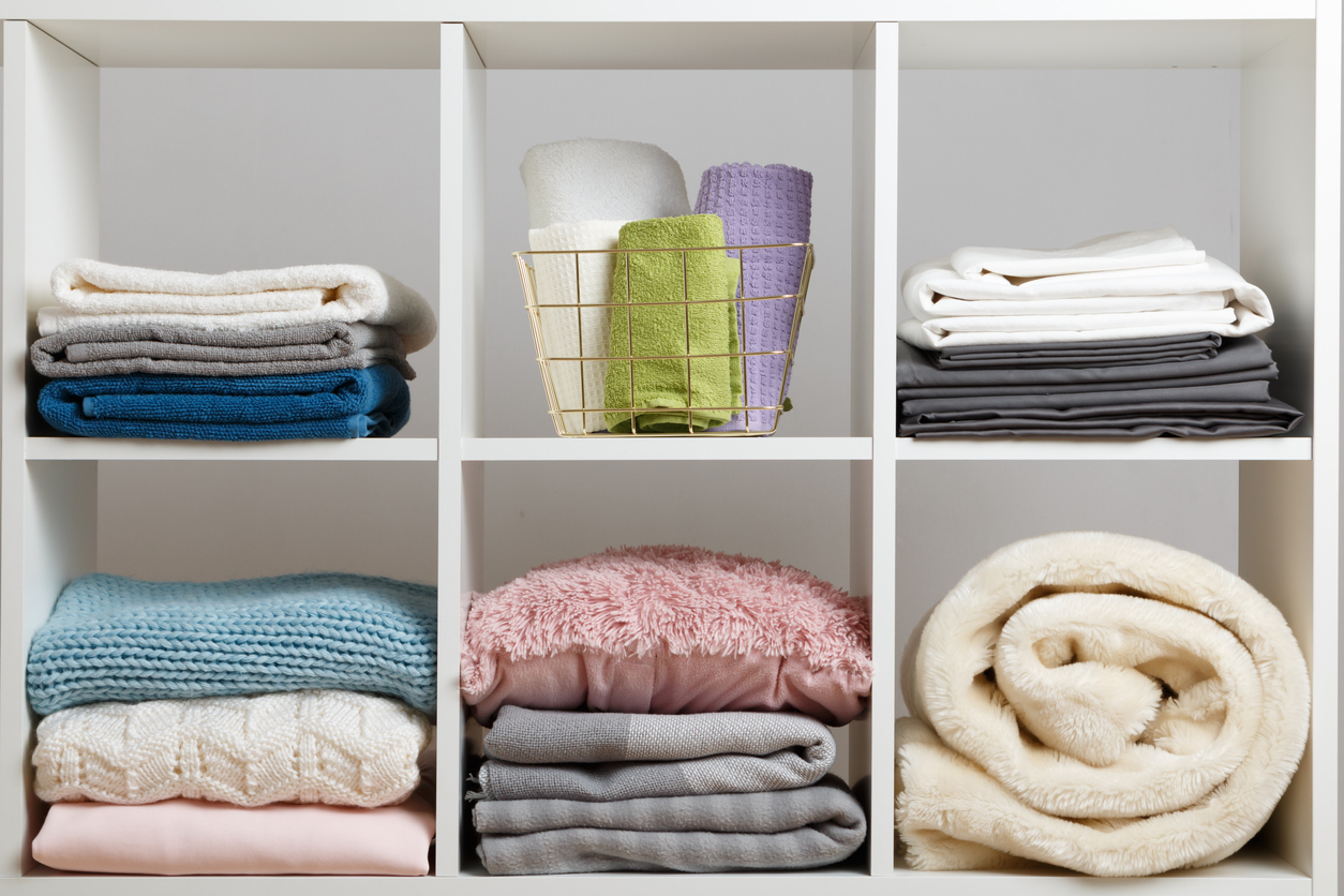 towels, sheets, bedding, clothes, blanket, and pillow on a white shelf