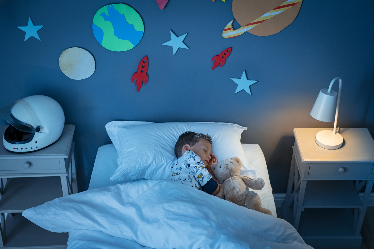 child sleeping on bed with solar system and planet decoration during the night