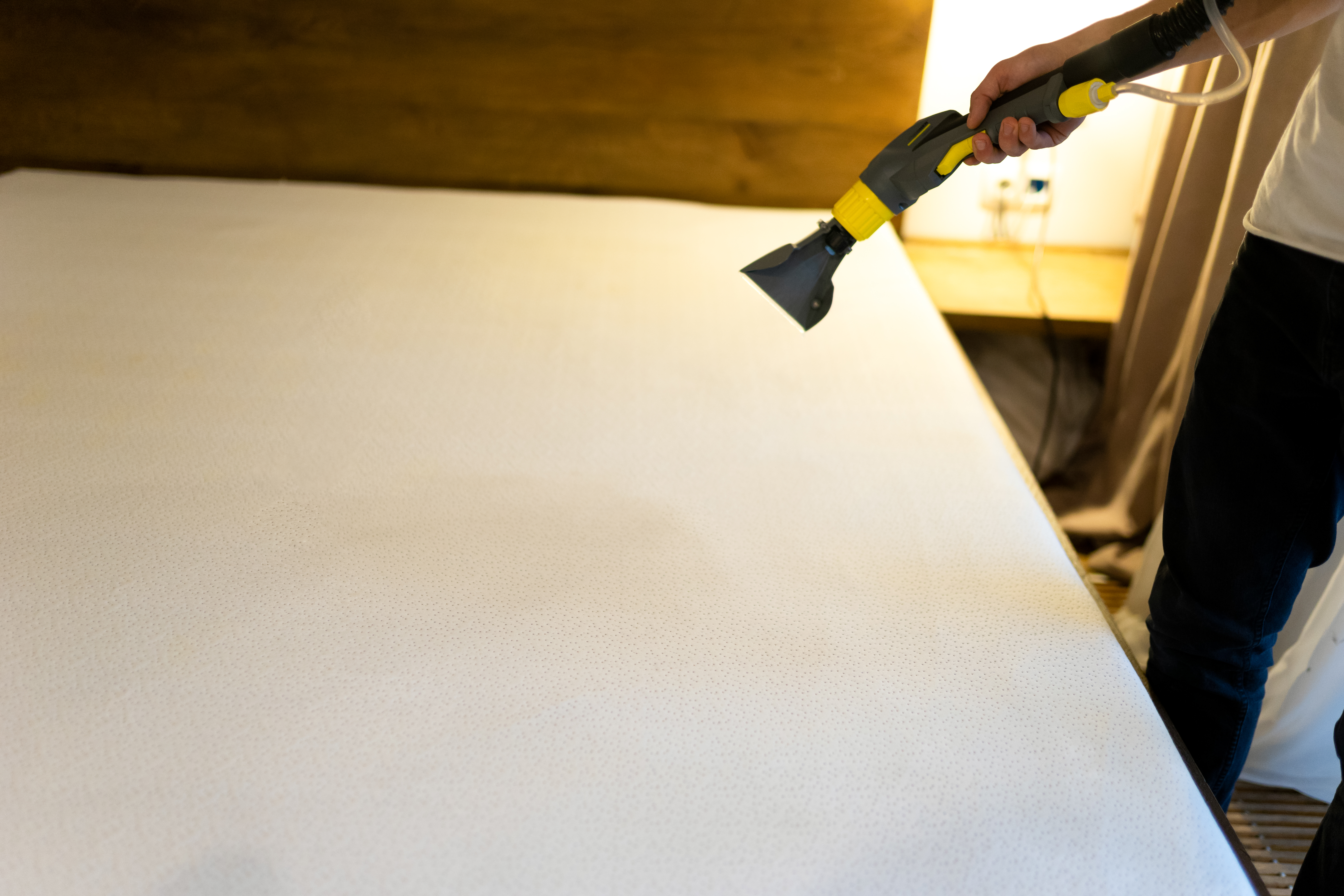 Man vacuuming the surface of a mattress
