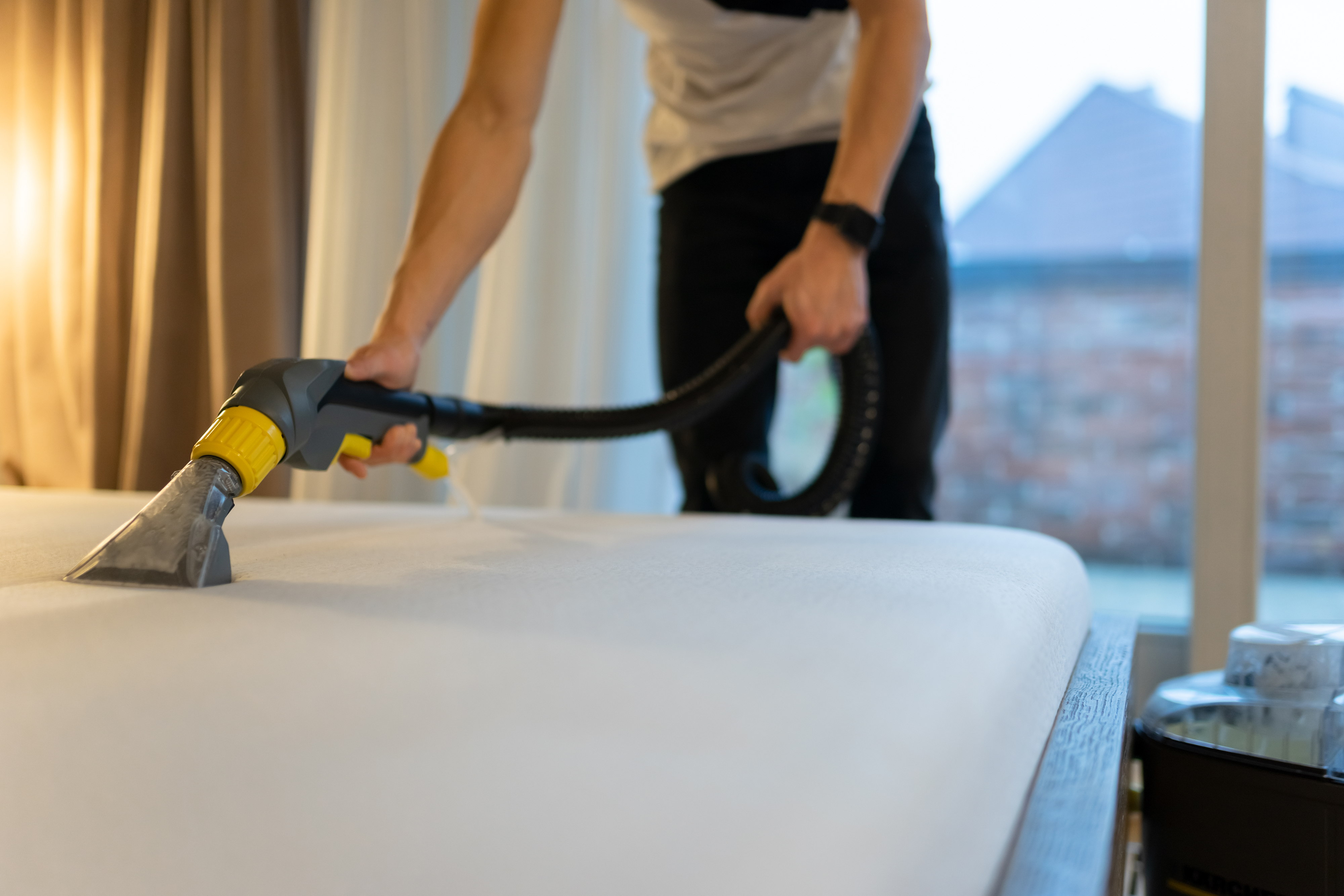 Person vacuuming the surface of a mattress 