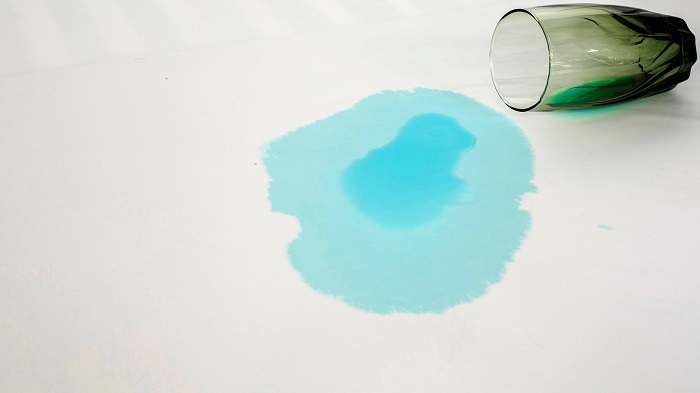 a blue drink being spilled and not absorbed by a Protect A Bed mattress protector