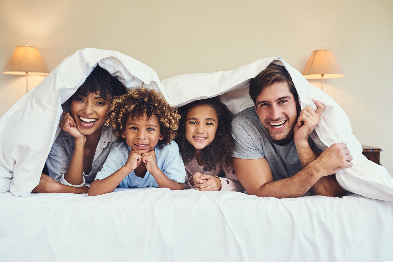 happy family relaxing together underneath a blanket at home
