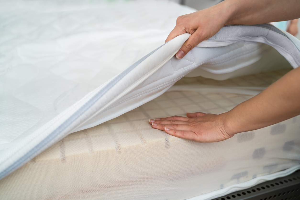 woman puts mattress protector on memory foam mattress