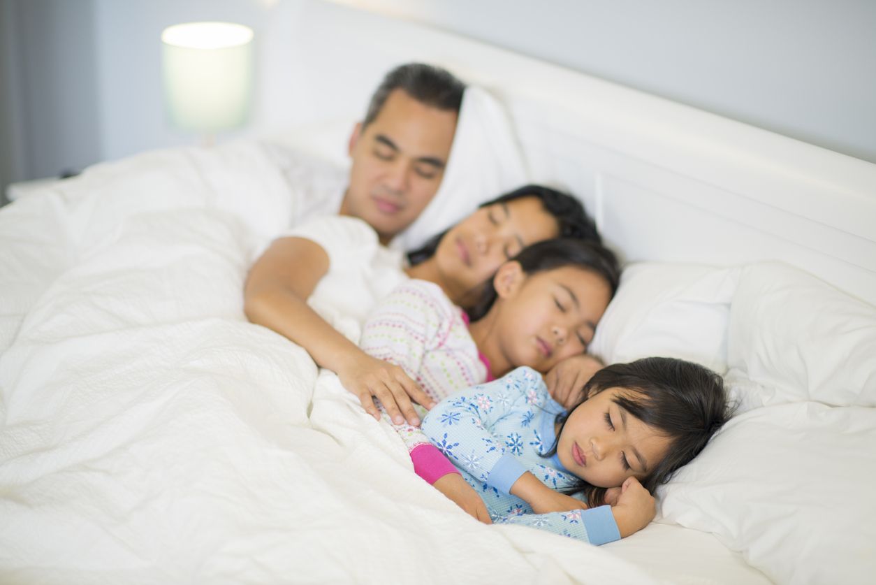 family of four fast asleep together in bed