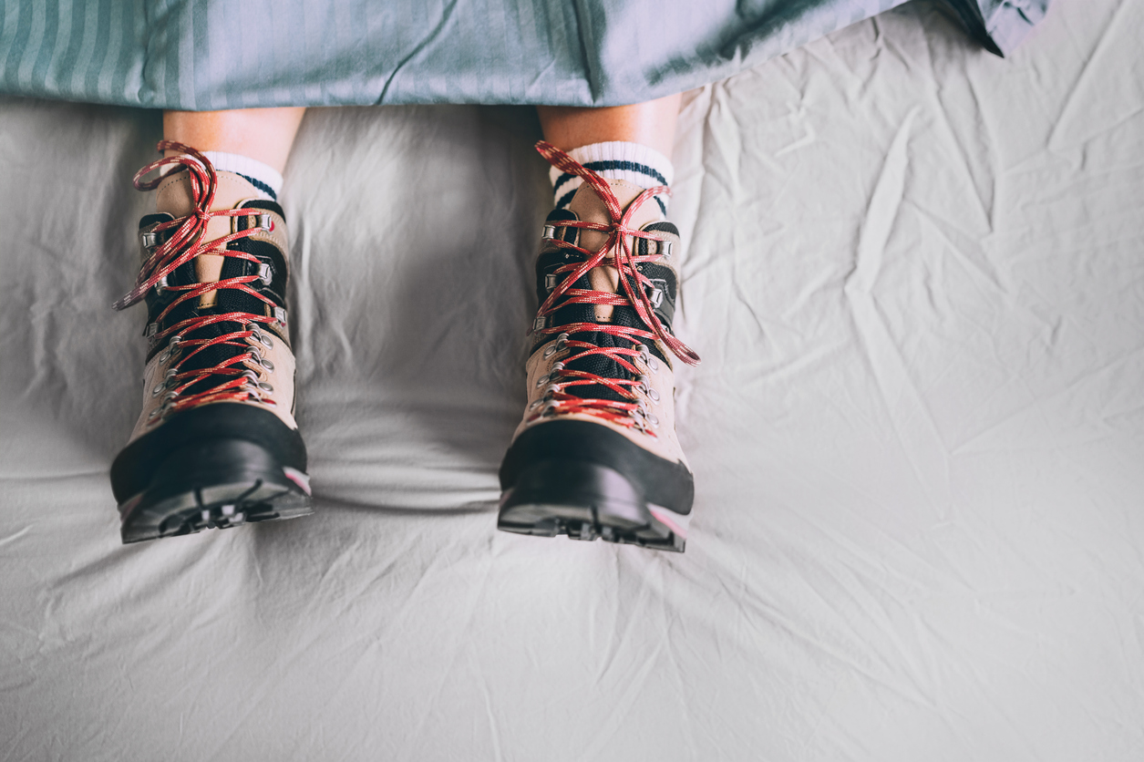 hiking boots on bedsheets
