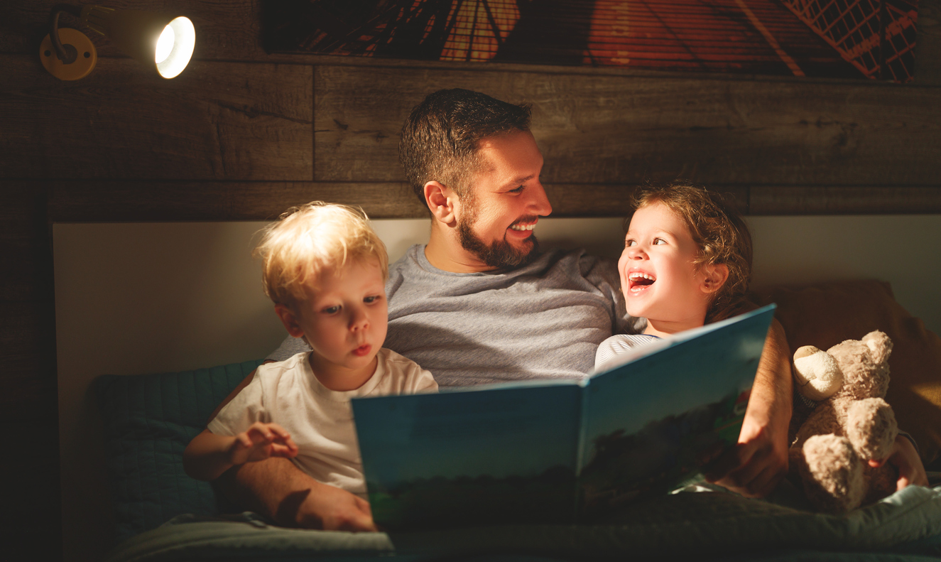 Dad and two sons read together before bed