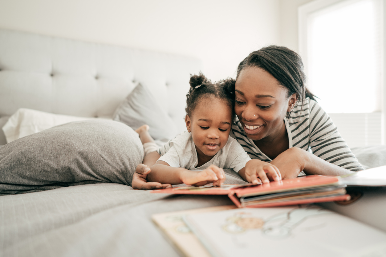 Mom and daughter read a book together in bed