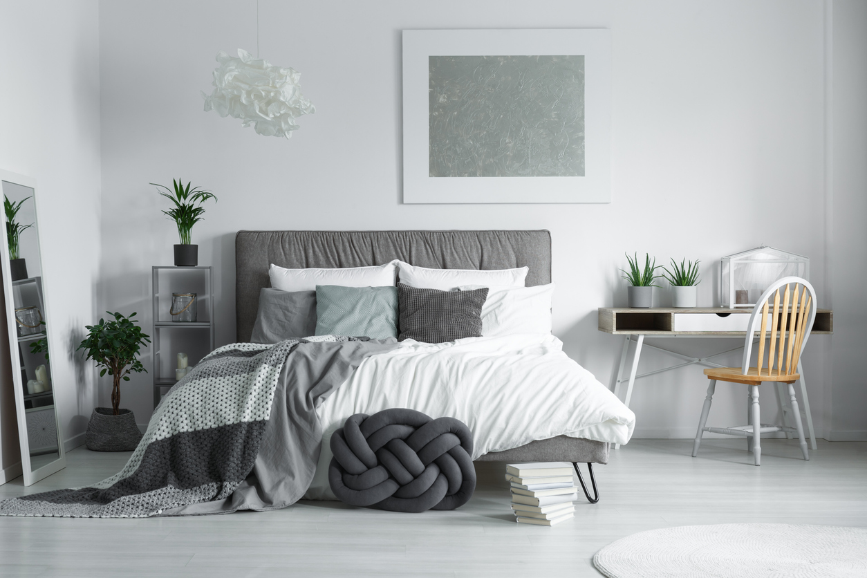 gray-themed bedroom with sage green accents including a large monochromatic painting
