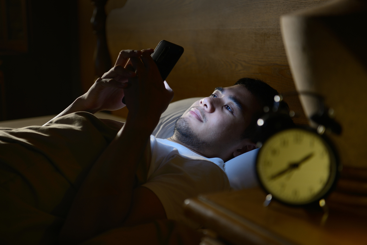 Man uses a bright smartphone in bed before he goes to sleep