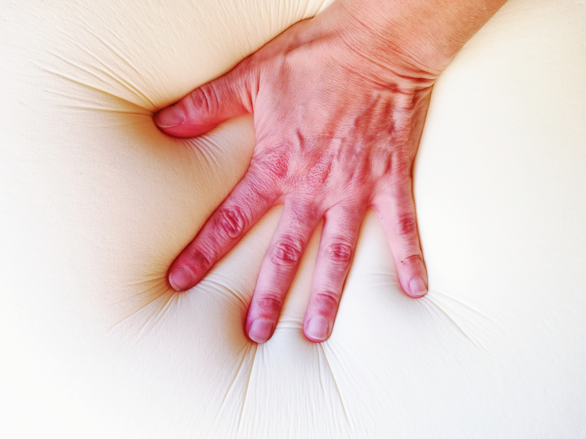 Hand pressing down on memory foam mattress