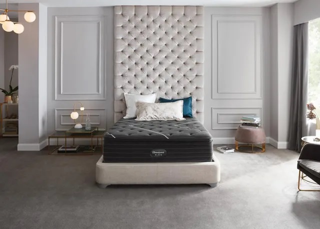 Modern bedroom with a gray interior and a black Beautyrest pillow top mattress sitting in the middle. 